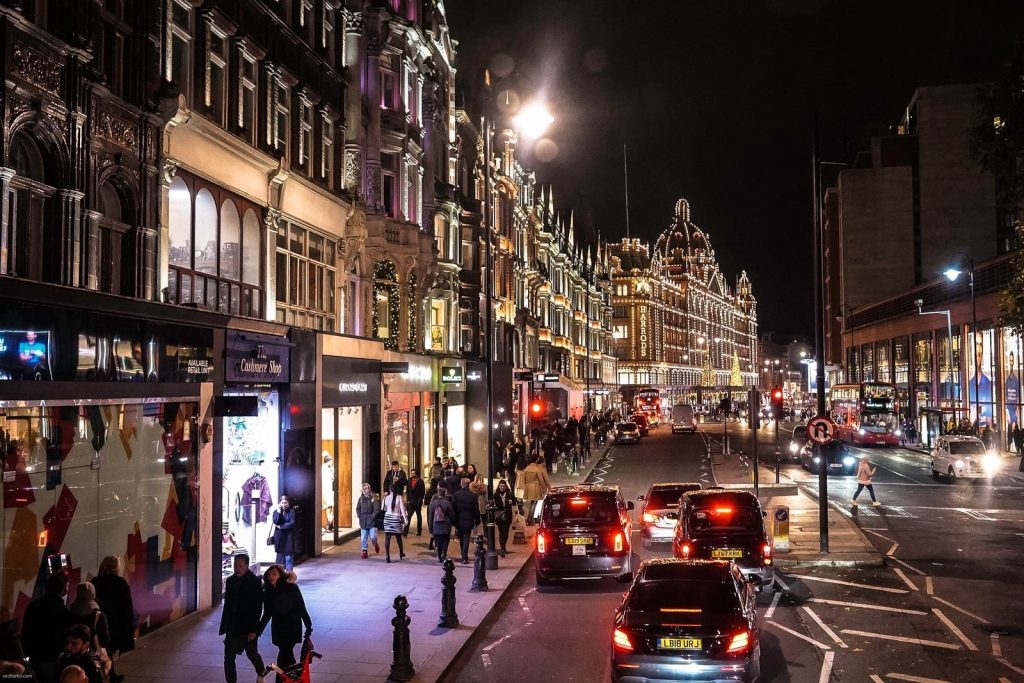 people walking on sidewalk near cars and buildings during night time