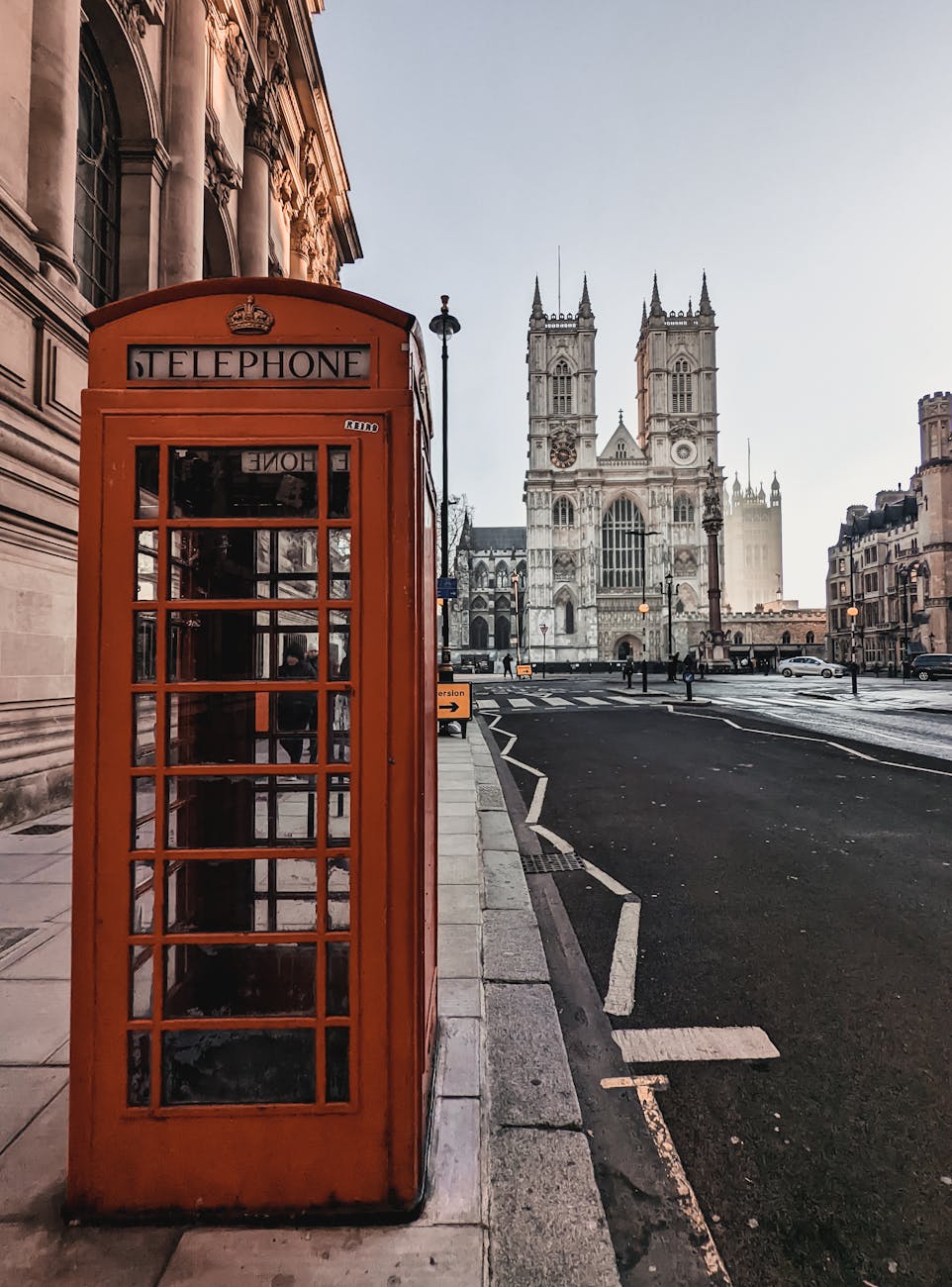 view of a red telephone booth and the westminster abbey in london england uk