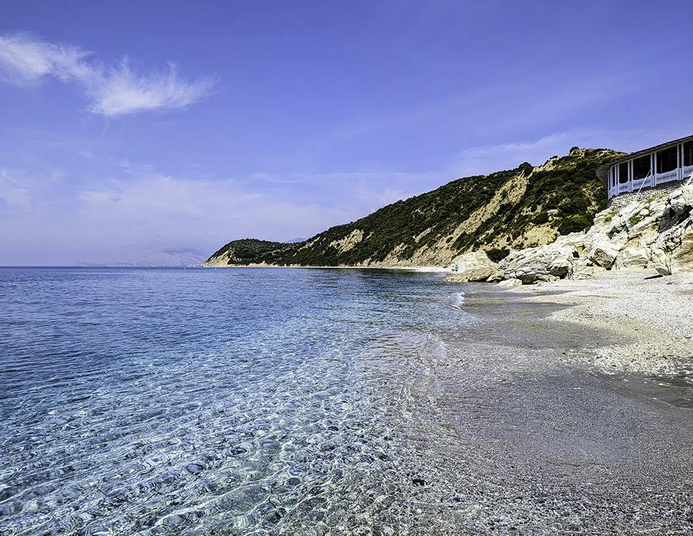 Blue water and pebble beach under a blue sky