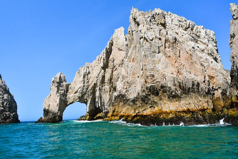 high cliff and blue sea with a large orifice in the cliff