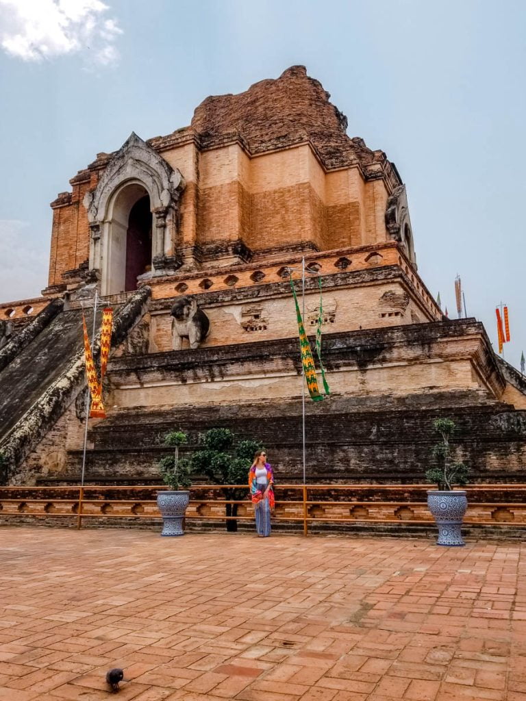 woman standing in front of a Thai temple with high stairs