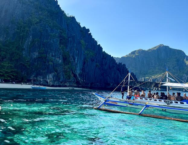 Boat transporting people on a transparent blue water in the Philippines