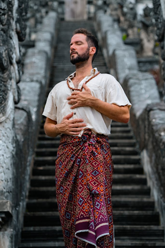 A Man in a Sarong Meditating at the Stairs