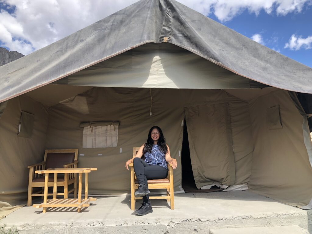 Woman sitting in front of a tent in the mountain by Asha BHATIA