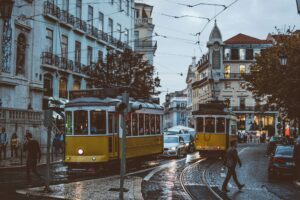 Two Yellow and White trams in a street with cars and pedestrian