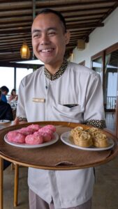 Smiling Balinese waiter presenting plates of local delicacies