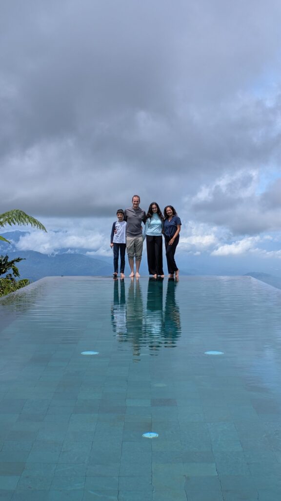 Family at the enf of an Infinity pool with cloudy blue sky in the background
